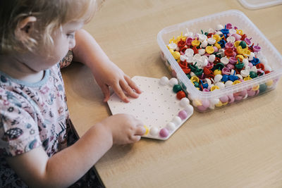 Girl playing board game on table at home