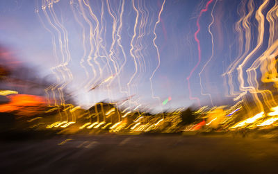 Light trails on road against sky at night