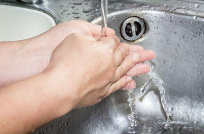 Cropped image of woman washing hands in sink