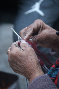 Cropped hand of senior woman knitting at home