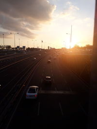 Vehicles on road against sky during sunset