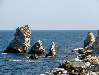 Rocks in sea against clear sky