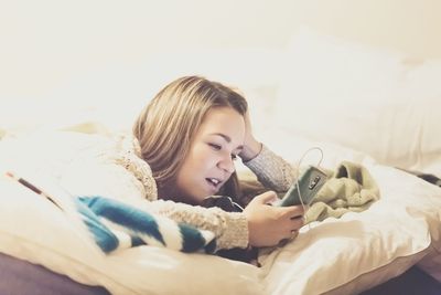 Woman listening to mp3 player on bed