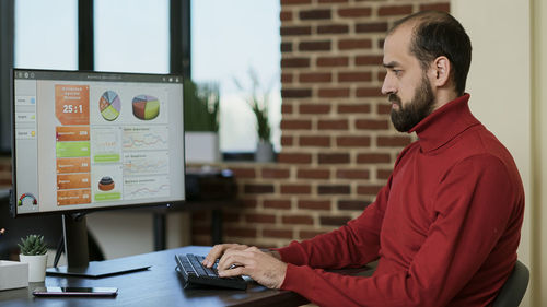 Side view of man using laptop at office