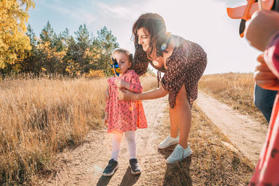 Mom shows little daughter how to use a windmill on outdoor. esg and clean energy concept.