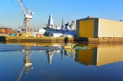 Reflection of factory on water against sky