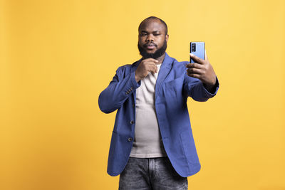 Young woman using mobile phone against blue background