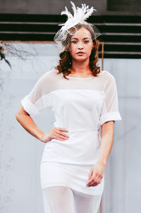 Female fashion model standing against wall