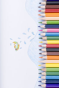 High angle view of colored pencils on white background