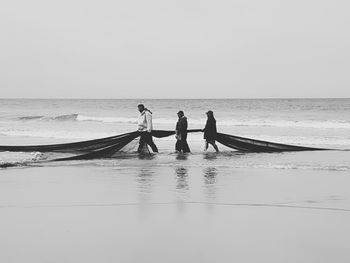 People at sea against clear sky