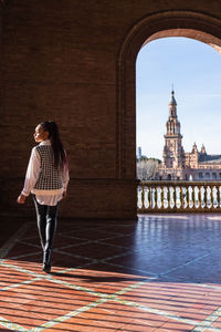 Back view of african american female with braids walking on plaza de espana on sunny day and looking away during weekend in seville