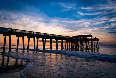 Pier over sea against sky at sunset