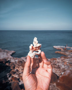 Midsection of man holding ice cream on sea shore