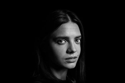 Close-up portrait of young woman over black background