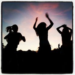 Silhouette people standing against sky at sunset