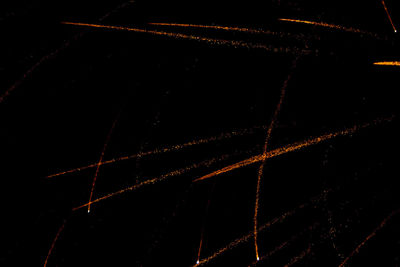 Low angle view of illuminated lighting equipment against black background