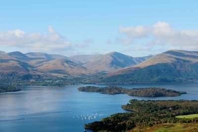 Scenic view of river by mountains against sky