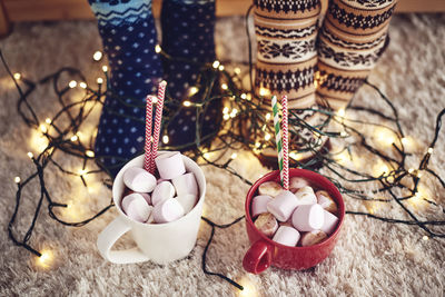 High angle view of marshmallow cups by string light during christmas