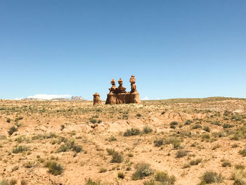 People sitting in desert against clear sky