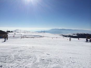 People walking on snow covered field against sky