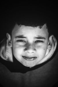 Portrait of smiling boy against black background