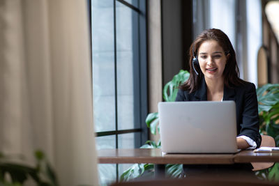 Portrait of a smiling young woman using phone