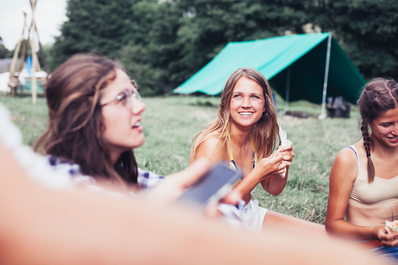 friendship, young adult, leisure activity, young women, real people, selective focus, lifestyles, women, togetherness, portrait, adult, communication, wireless technology, holding, people, happiness, smiling, group of people, day, outdoors