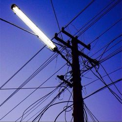 Low angle view of electricity pylon against blue sky