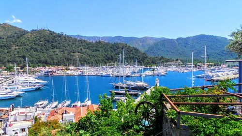 Boats moored at harbor against clear blue sky