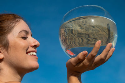 Close-up of man holding crystal ball against sky