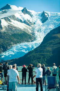 Rear view of people walking on snowcapped mountain against sky