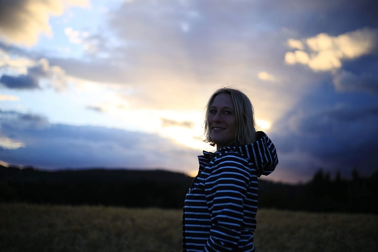 sky, sunset, one person, striped, standing, nature, beauty in nature, leisure activity, field, land, cloud - sky, young adult, real people, young women, casual clothing, waist up, lifestyles, women, portrait, outdoors, hairstyle, beautiful woman