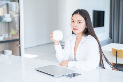 Young woman with coffee cup sitting at home