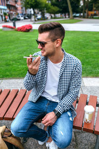 Man holding cigarette while sitting outdoors