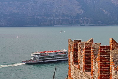 High angle view of ship sailing on sea against mountains