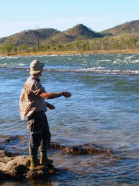 Man fishing on rock in sea