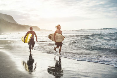 Men with surfboards running at shore