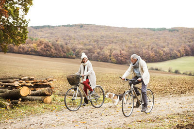 Senior couple doing a bicycle trip with dog in autumn