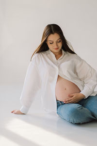 Portrait of young woman standing against white background