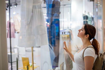 Woman looking through window at store