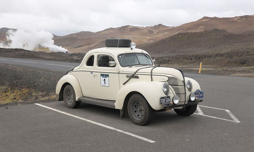 Vintage car on road against mountain range