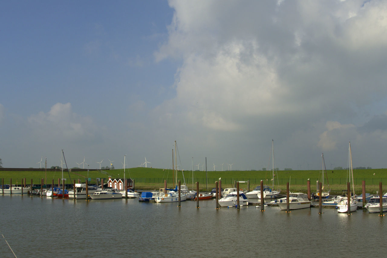 BOATS MOORED IN HARBOR AGAINST SKY