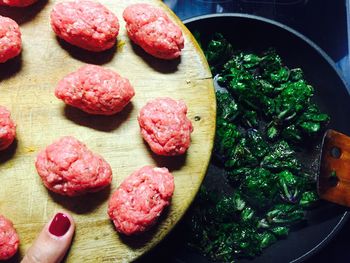 Cropped image of woman holding meat on cutting board while preparing food