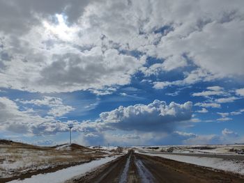 Road amidst field against sky