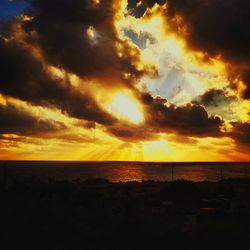 Scenic view of sea against cloudy sky during sunset