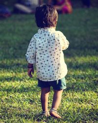 Rear view of boy walking on field