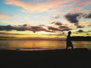 Silhouette people on beach at sunset