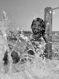 Portrait of smiling man amidst splashing water