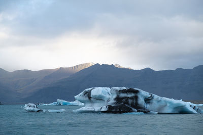 Scenic view of iceberg, sea and mountains against sky in the southern coast of iceland 