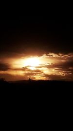 Silhouette landscape against dramatic sky during sunset